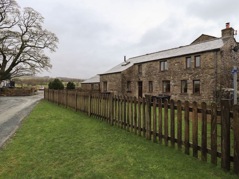 A house with a fence and tree at Orcaber Farm Barn in Lancaster