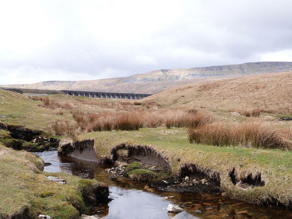 A landscape with a stream and a viaduct at Orcaber Farm Barn Lancaster