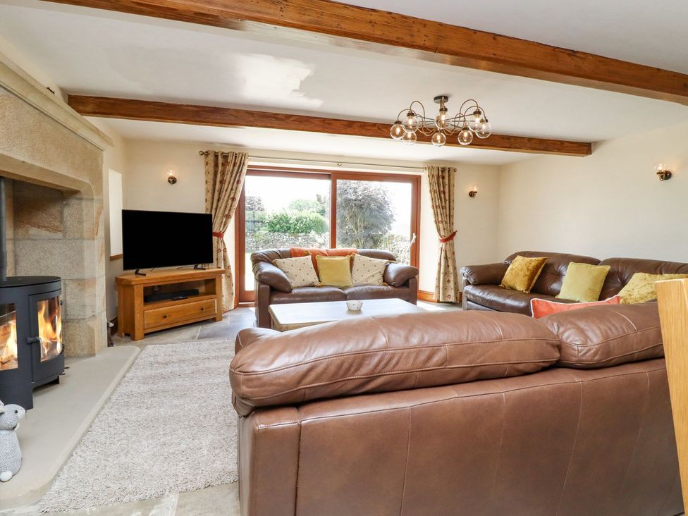 A living room with a fireplace and a television at Orcaber Farmhouse in Lancaster