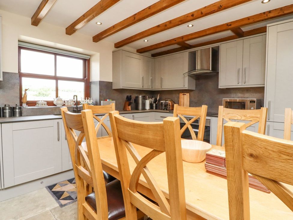 A kitchen with a dining table and cabinets at Orcaber Farmhouse in Lancaster