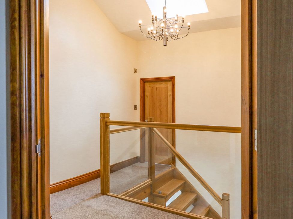 A hallway with a chandelier and a staircase at Orcaber Farmhouse in Lancaster