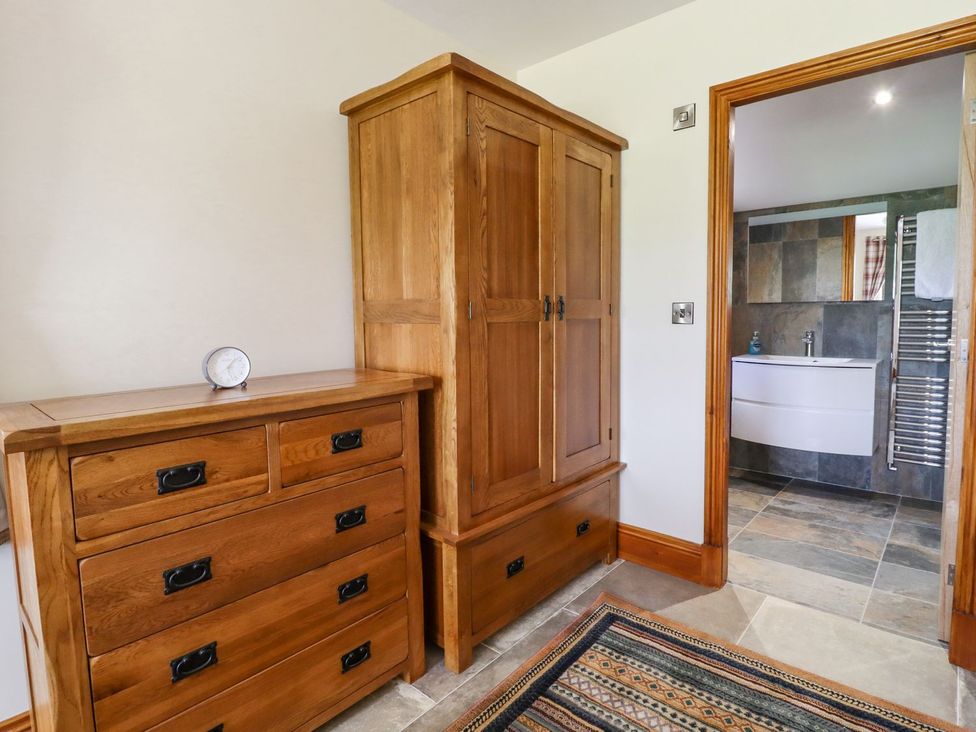 A bathroom with wooden furniture and a view into another bathroom at Orcaber Farmhouse Lancaster