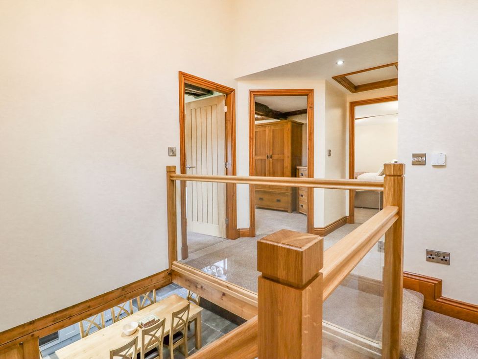 A hallway with a railing and doors at Orcaber Farmhouse in Lancaster