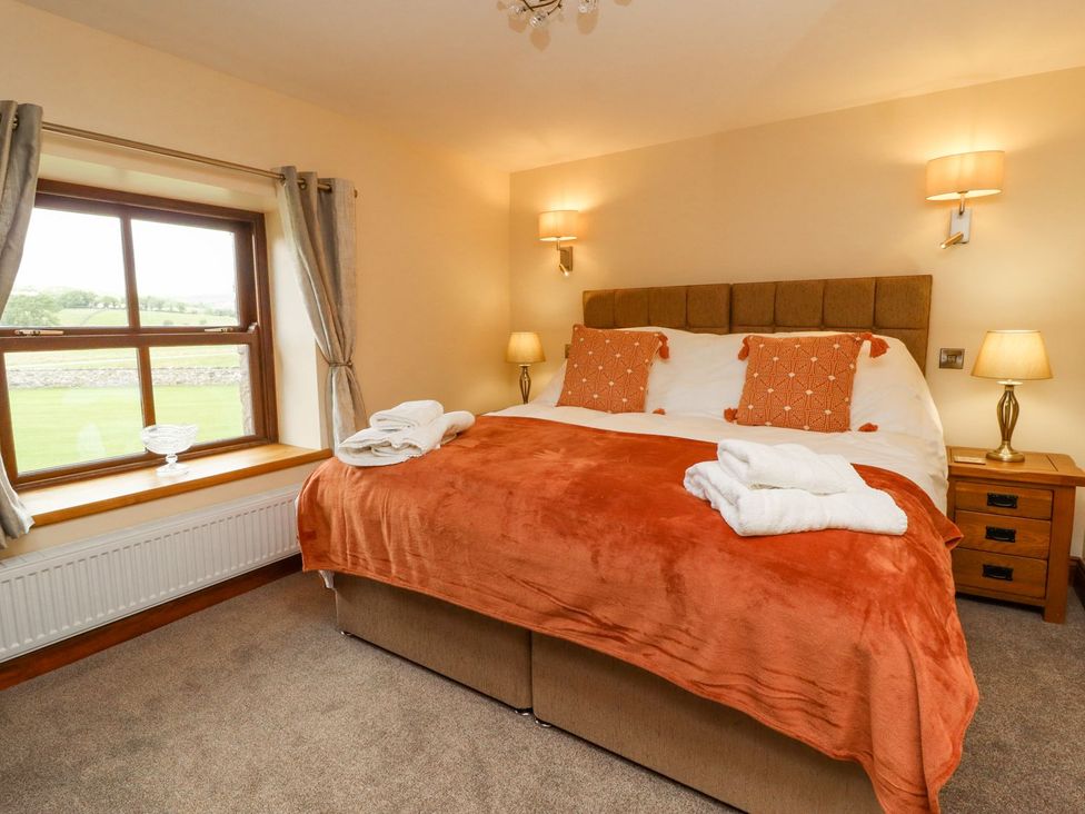 A bedroom with a double bed and windows at Orcaber Farmhouse in Lancaster