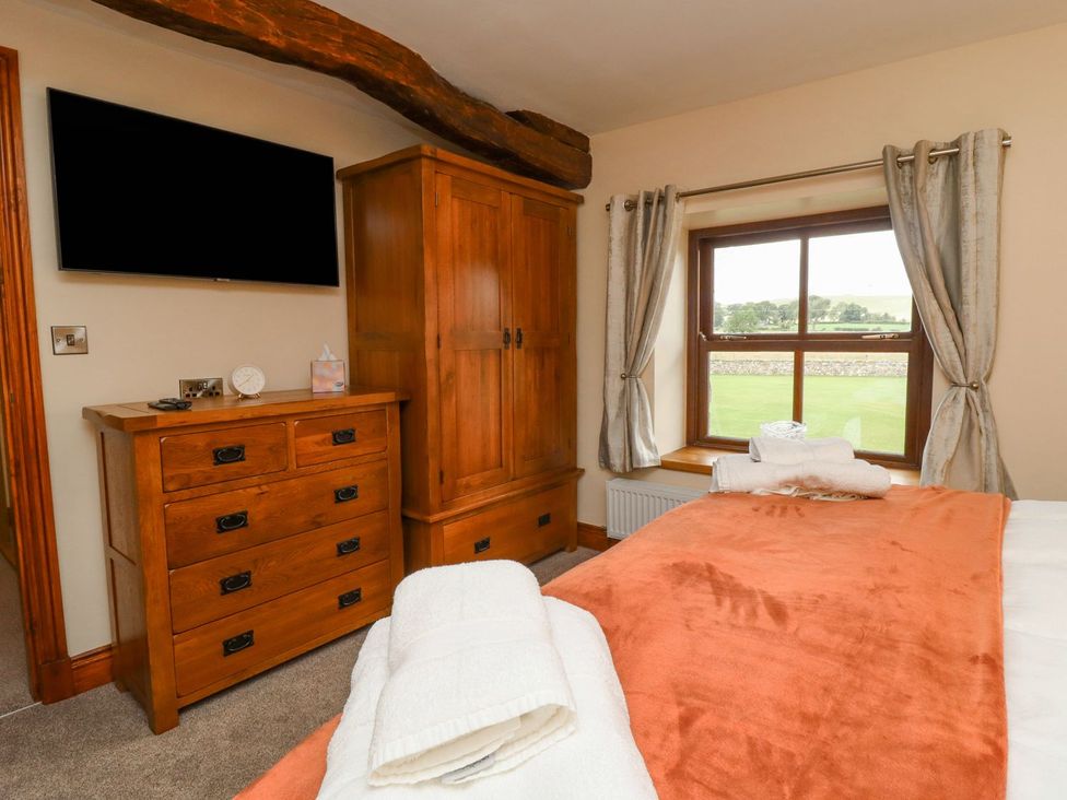 A bedroom with a wardrobe and television at Orcaber Farmhouse in Lancaster