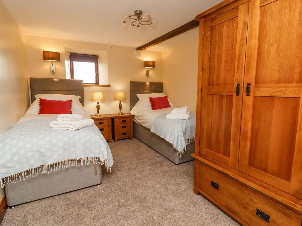 A bedroom with two single beds and a wardrobe at Orcaber Farmhouse Lancaster