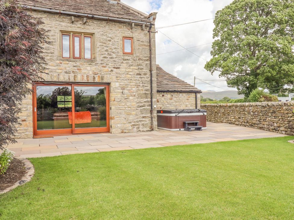 An outdoor area with a hot tub and a stone building at Orcaber Farmhouse in Lancaster