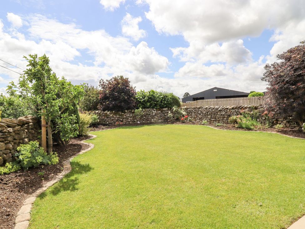 A garden with grass and stone walls at Orcaber Farmhouse in Lancaster