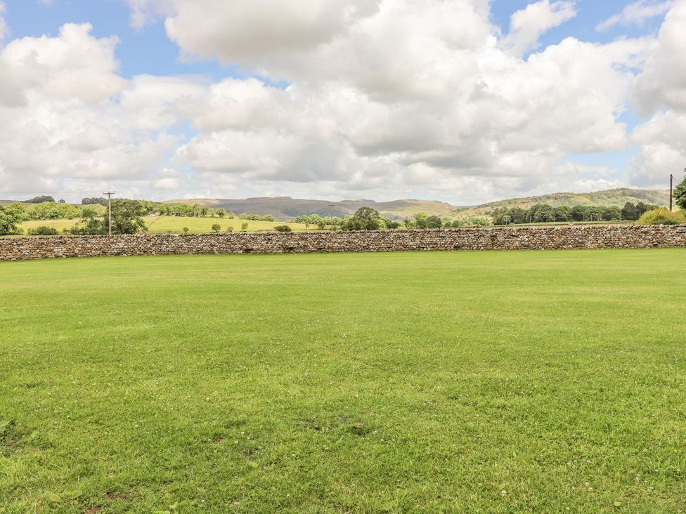 A grassy area with a stone wall and hills at Orcaber Farmhouse in Lancaster