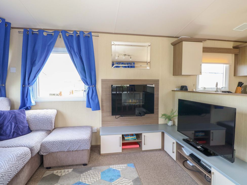 A living room with a sofa and televisions at PK Sunset View in Corton