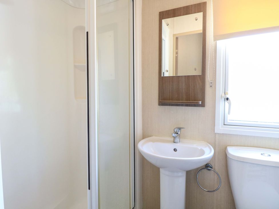 A bathroom with a sink, toilet, shower, and mirror at PK Sunset View in Corton