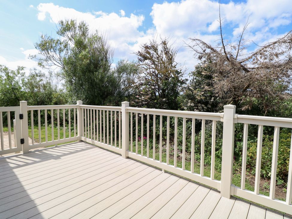 A deck area with railing and trees in the background at PK Sunset View in Corton