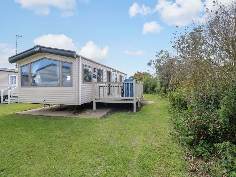 A mobile home with a decking area and lawn at PK Sunset View in Corton