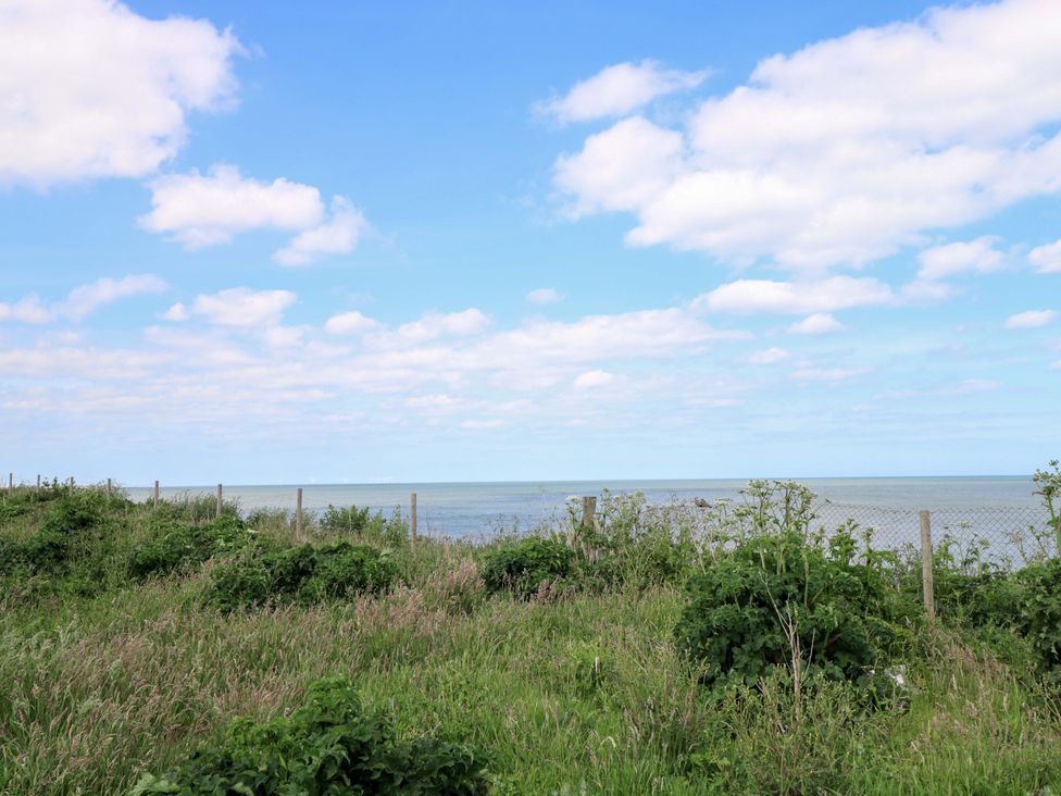 A view of the ocean with grass and a fence at PK Sunset View in Corton