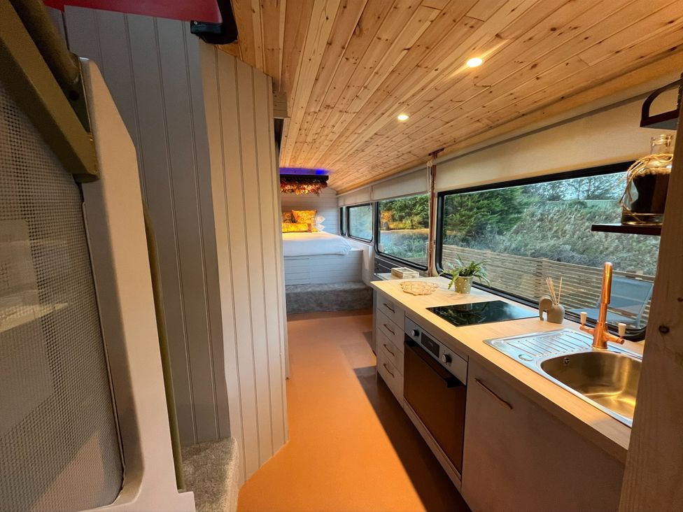 A kitchen with a stove sink and a bed in a converted bus at No 1 The Depot in Gateshead
