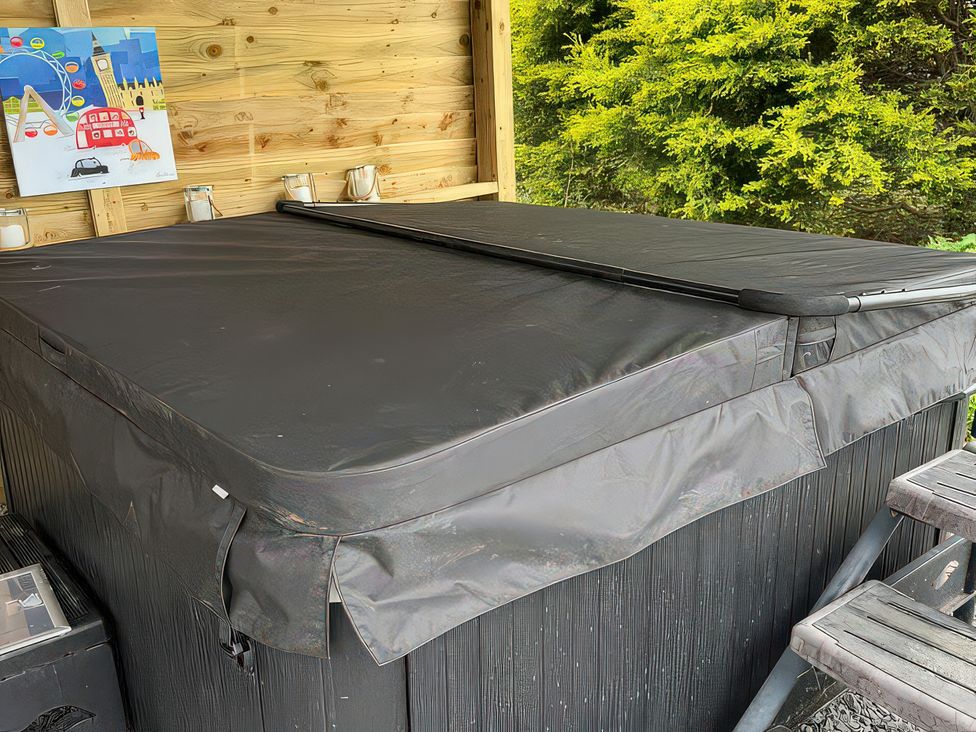A hot tub covered with a black cover in a wooden outdoor structure at No 1 The Depot in Gateshead