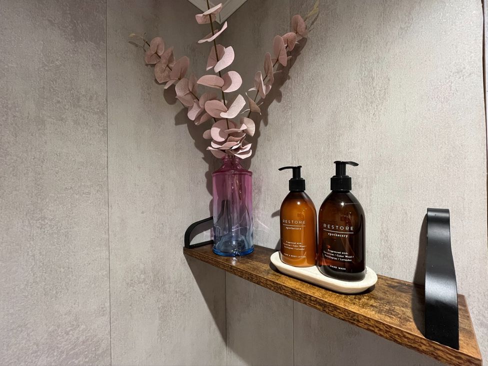 A shelf with hand wash and lotion bottles next to a vase with dried flowers at No 1 The Depot in Gateshead