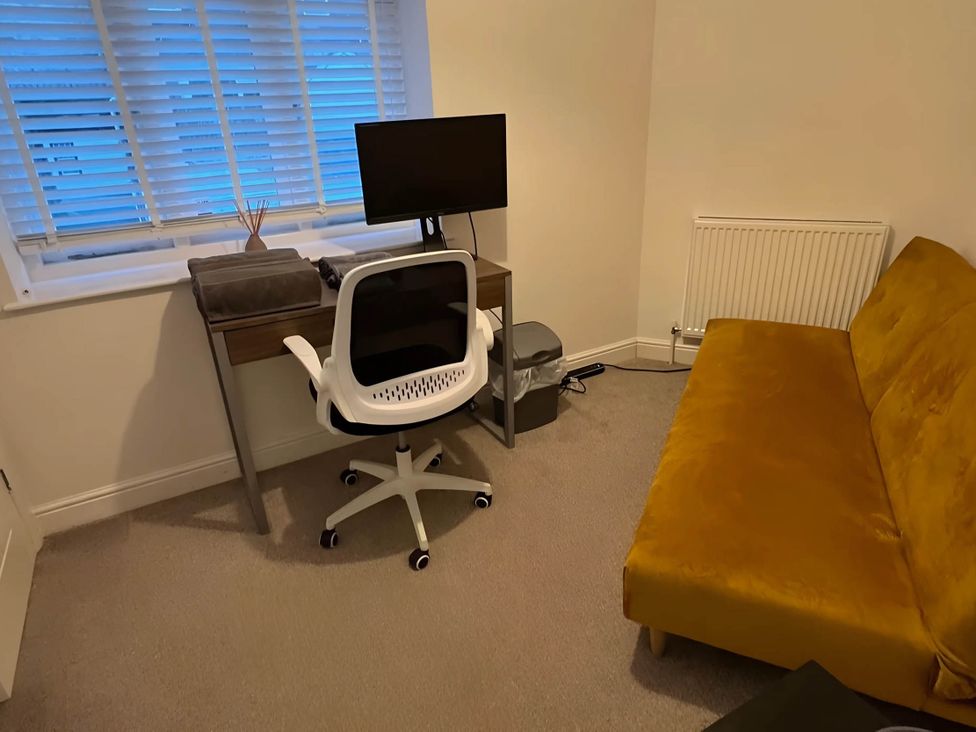 A workspace with a desk, computer monitor, chair, and sofa at Seaside Cottage Escape in Paignton