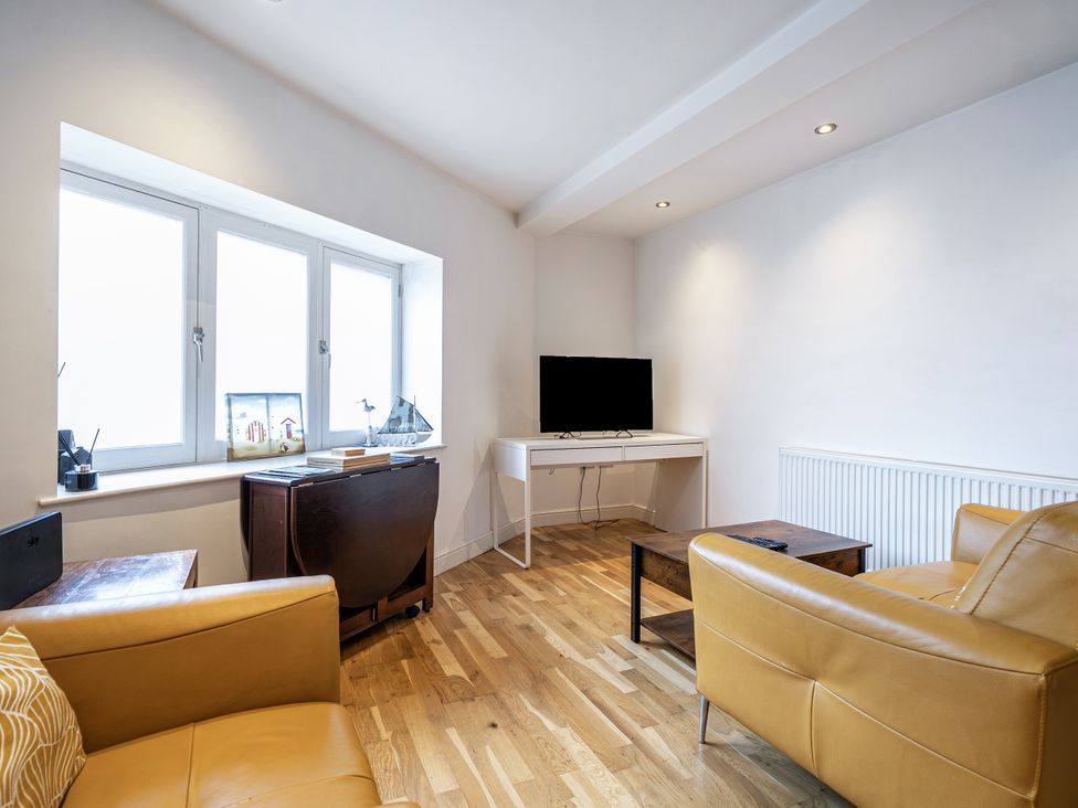 A living room with a television and sofa at Seaside Cottage Escape in Paignton