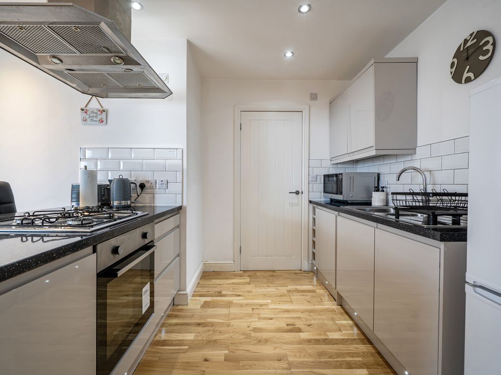 A kitchen with modern appliances and wooden flooring at Seaside Cottage Escape in Paignton