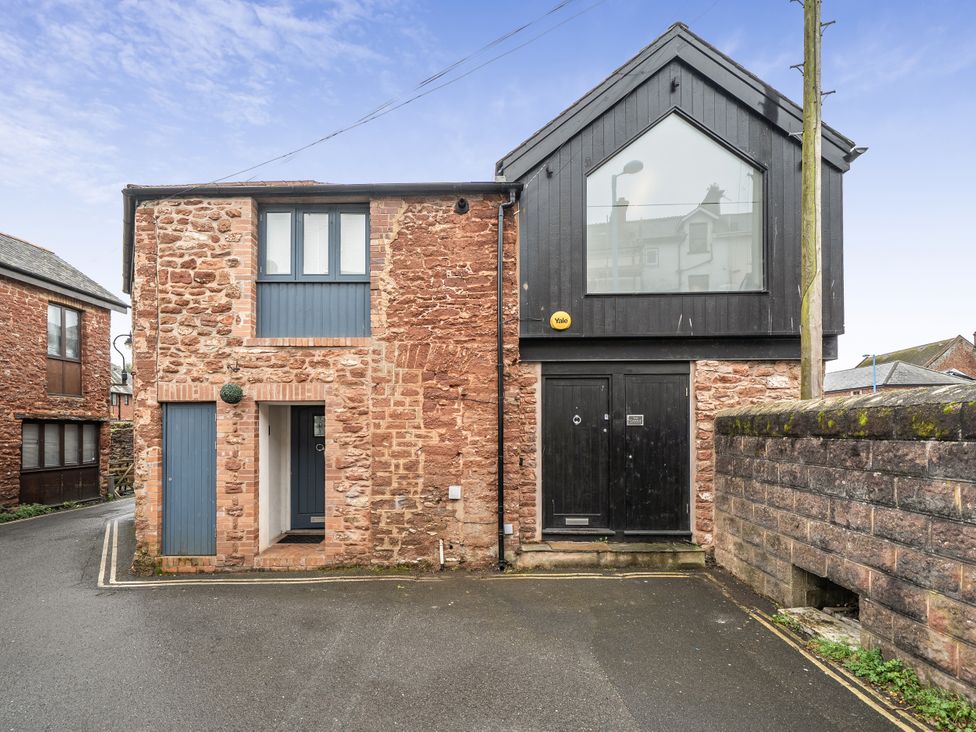 A stone building with a black door and windows at Seaside Cottage Escape in Paignton