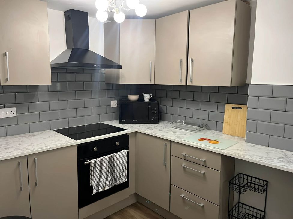 A kitchen with countertop, oven, microwave, and cabinets at Llangollen - House - Sleeps 8- Garden in Llangollen