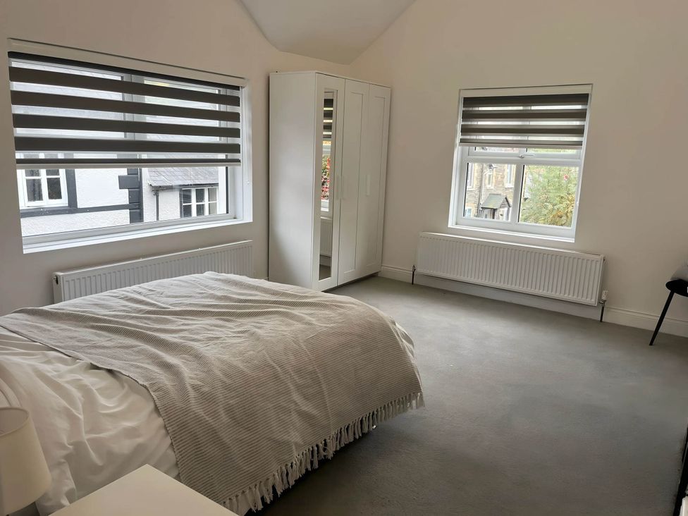 A bedroom featuring a bed, wardrobe, radiator, and windows at Llangollen - House - Sleeps 8- Garden in Llangollen