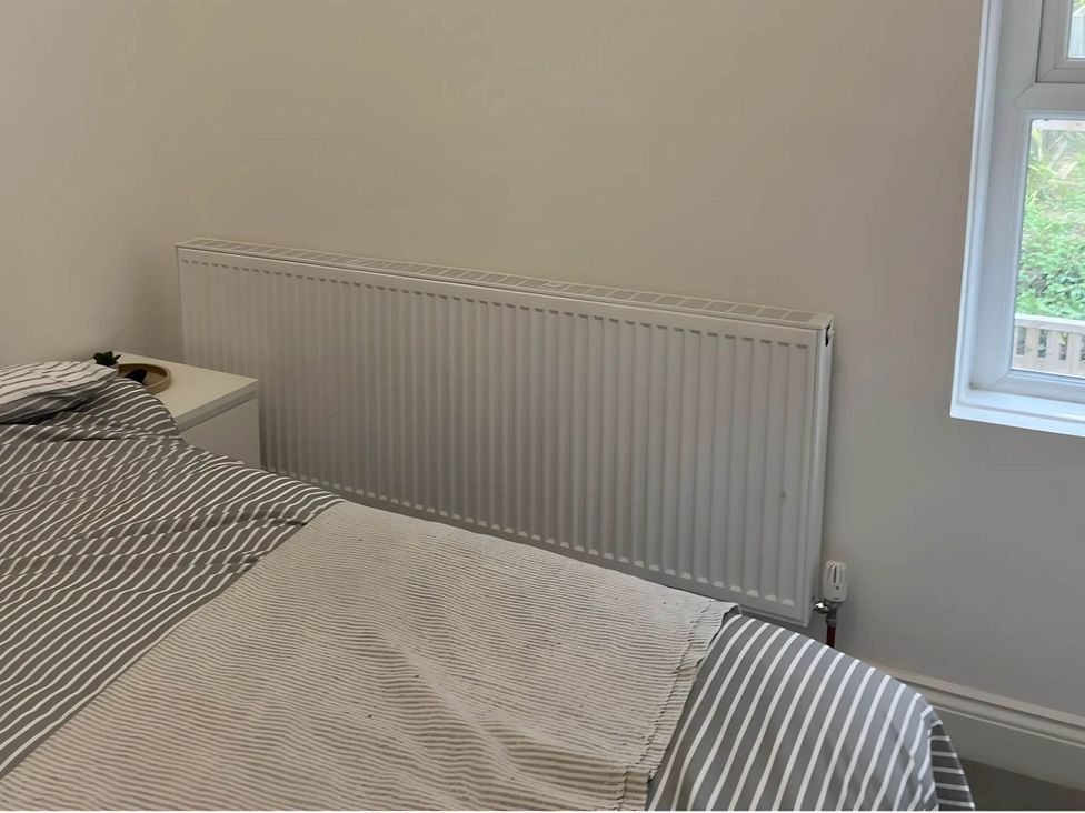 A bedroom with a bed and a radiator at Llangollen - House - Sleeps 8- Garden, Llangollen