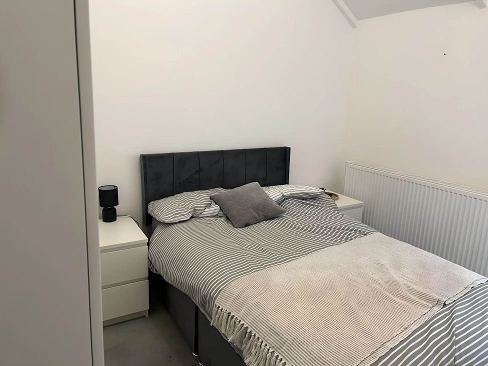 A bedroom with a bed, bedside table, lamp and radiator at Llangollen - House - Sleeps 8- Garden, Llangollen