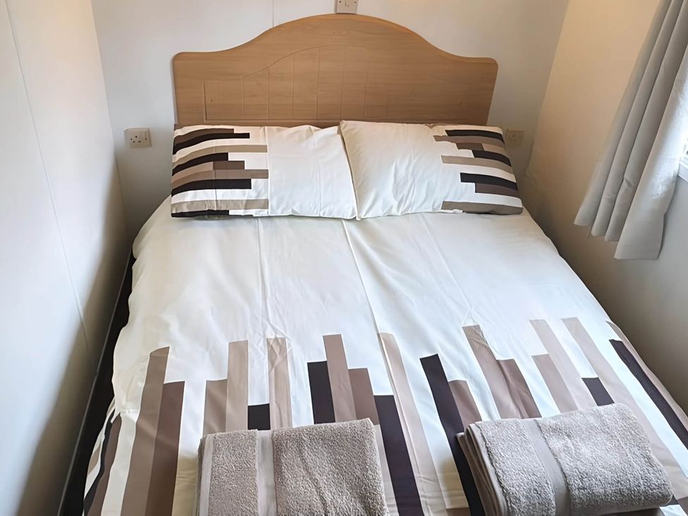 A bed with pillows and towels in a bedroom at Llanarmon-yn-Ial Mold 3-Bed Caravan, Sleeps 6 Llanarmon-Yn-Ial