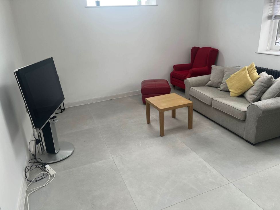 A living room with a television, sofa, armchair, and coffee table at Modern Seaside Cottage - Sleeps 5, Paignton