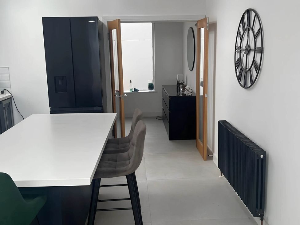 A kitchen with a refrigerator and bar stools at Modern Seaside Cottage - Sleeps 5, Paignton