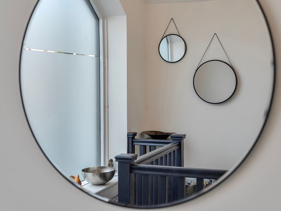 A hallway with mirrors and a bowl on a railing at Modern Seaside Cottage - Sleeps 5 in Paignton