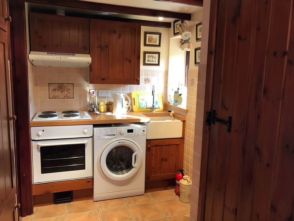 A kitchen with a washing machine and stove at Converted Stone Barn -20 Acres - Farm Animals! Corwen