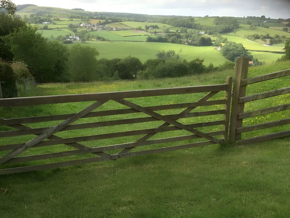 A view of a field with a wooden gate at Converted Stone Barn -20 Acres - Farm Animals in Corwen
