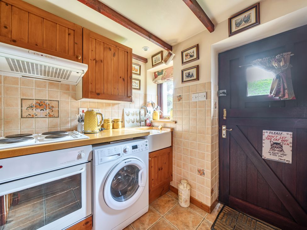 A kitchen with an oven and washing machine at Converted Stone Barn -20 Acres - Farm Animals! in Corwen
