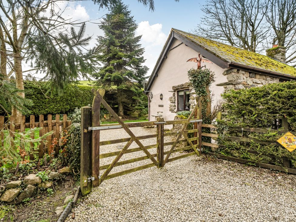 A house with a gravel driveway and wooden gate at Converted Stone Barn -20 Acres - Farm Animals! in Corwen