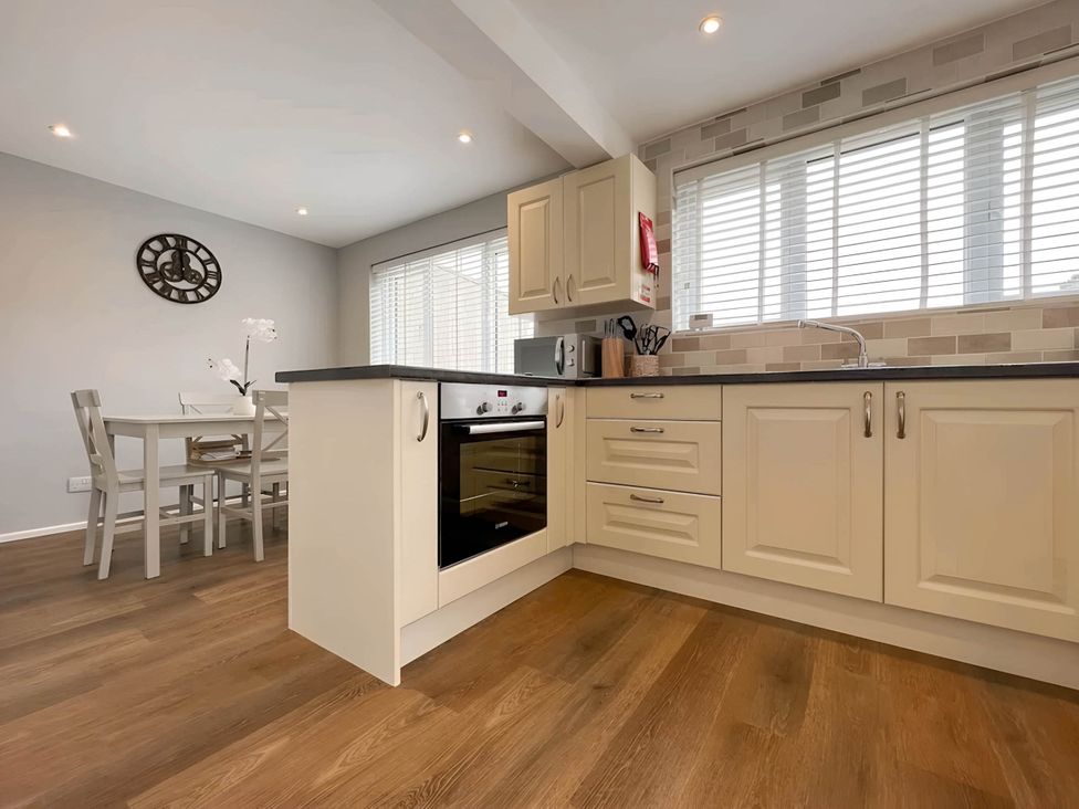 A kitchen with appliances and a dining table at 2 Bed House - Sleeps 4 - Garden - Parking - Wifi in Kendal