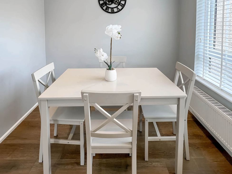 A dining table with chairs and a clock at 2 Bed House - Sleeps 4 - Garden - Parking - Wifi, Kendal
