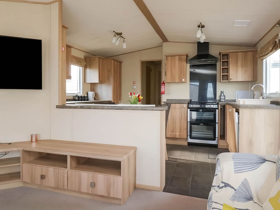 A living room with a kitchen area featuring a television and an oven at CaravanSleeps6-FreeParking-QuietRetreat-Nature in Paignton