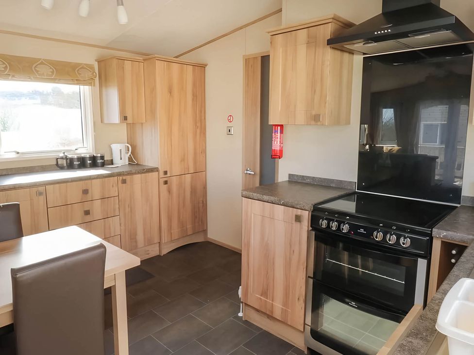 A kitchen with cabinets, stove, and kettle at CaravanSleeps6-FreeParking-QuietRetreat-Nature in Paignton