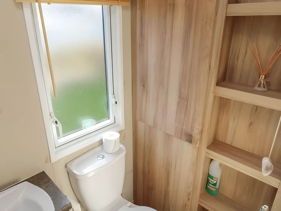 A bathroom with a toilet and a shelf at CaravanSleeps6-FreeParking-QuietRetreat-Nature in Paignton