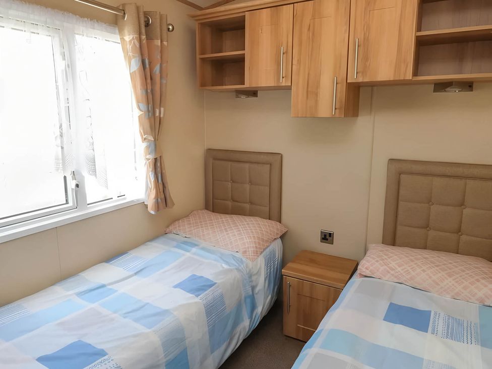 A bedroom with two beds and curtains at CaravanSleeps6-FreeParking-QuietRetreat-Nature in Paignton