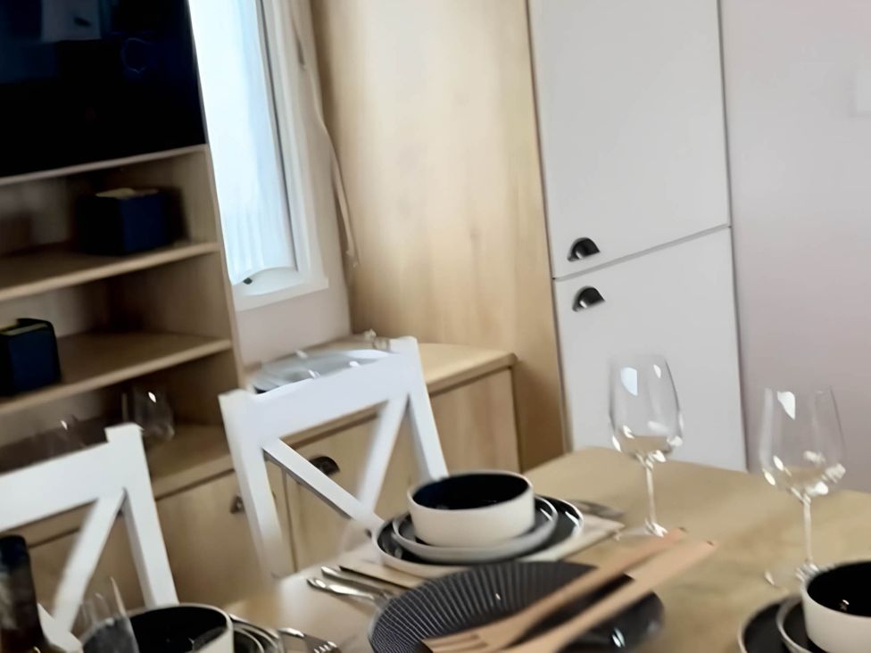 A dining area with table settings and kitchenette at 293 Static caravan Beverley Bay Paignton