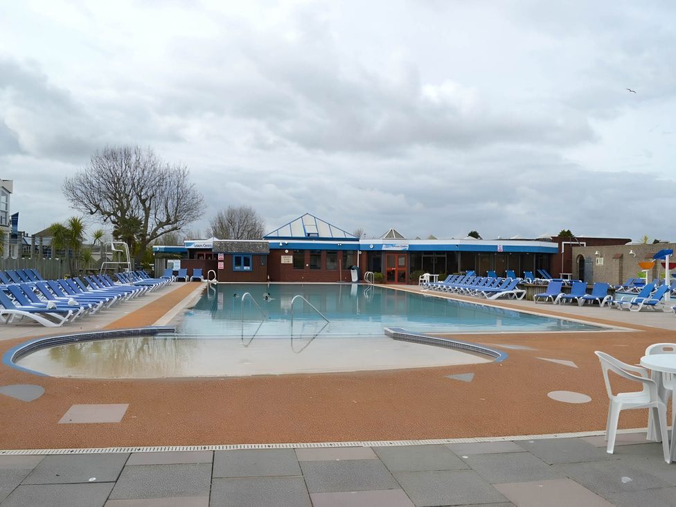 An outdoor pool area with sun loungers and a building at 293 Static caravan Beverley Bay Paignton