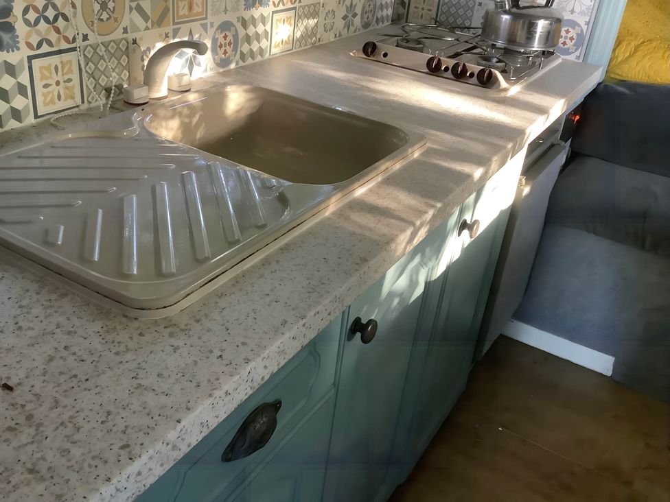 A kitchen with a sink and gas stove at Dobbin the horse box in The Lake District