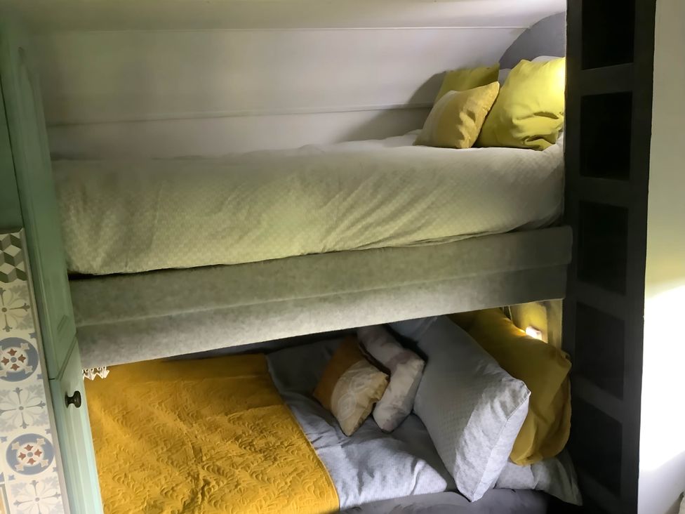 A bunk bed with pillows and blankets in Dobbin the horse box in The Lake District