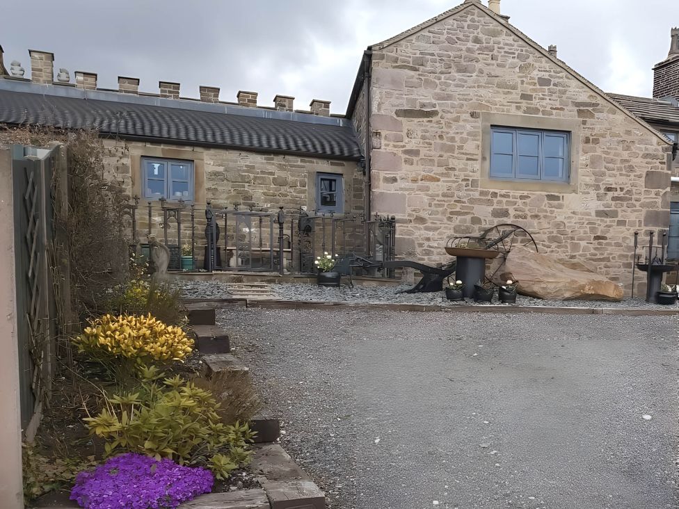 A stone house with a metal fence and flower bed at 1 Bed Cottage - Sleeps 3 - Garden - Parking - Wifi Buxton