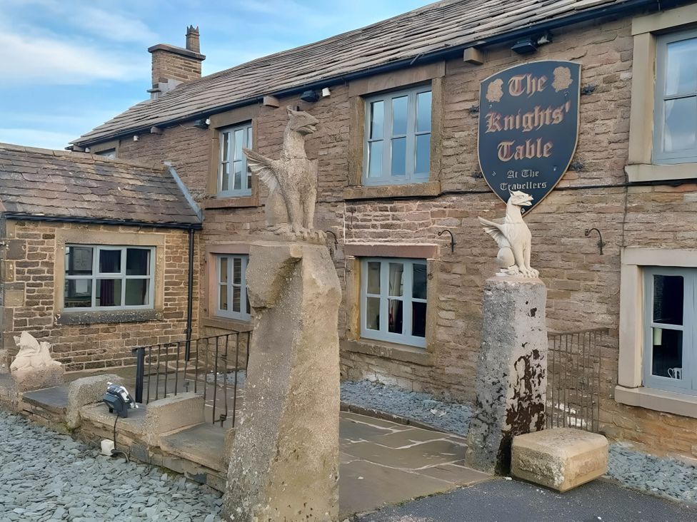 An outdoor view of The Knights' Table with stone sculptures and windows in Buxton
