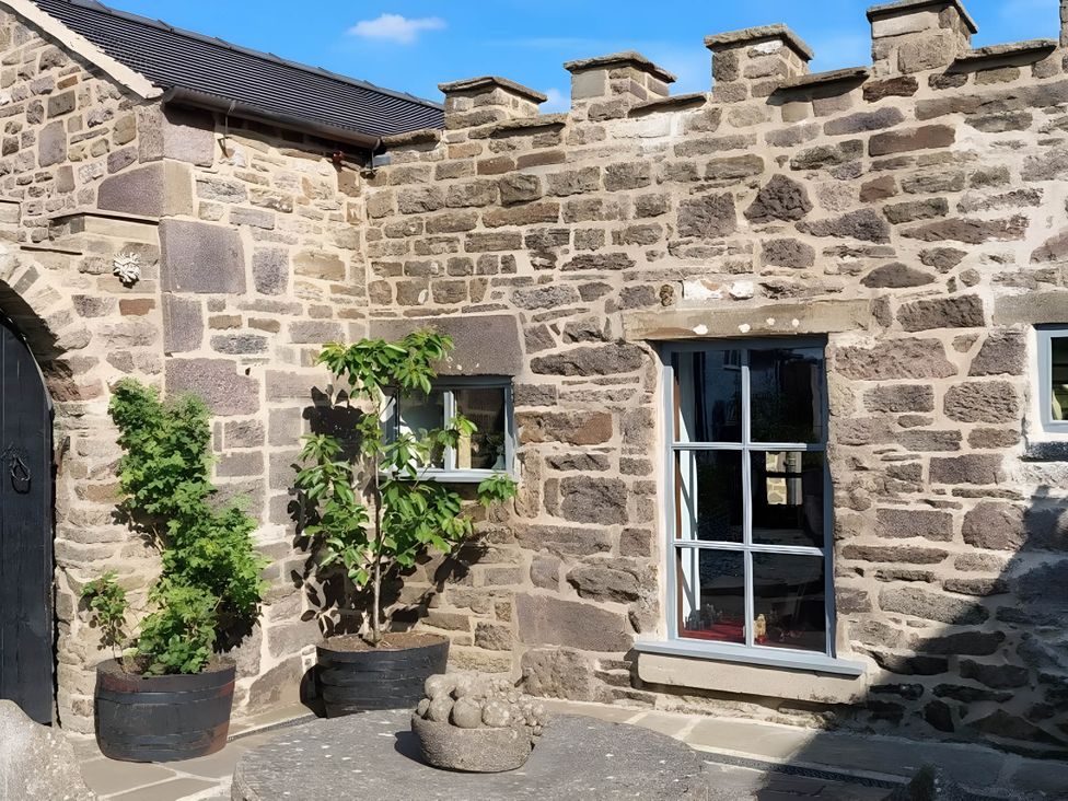 An outdoor view of a stone wall with a door and windows at 1 Bed Cottage - Sleeps 3 - Garden - Parking - Wifi in Buxton